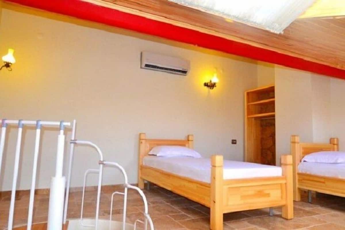 A room with two wooden beds, a white radiator, an air conditioning unit, and a white chair.