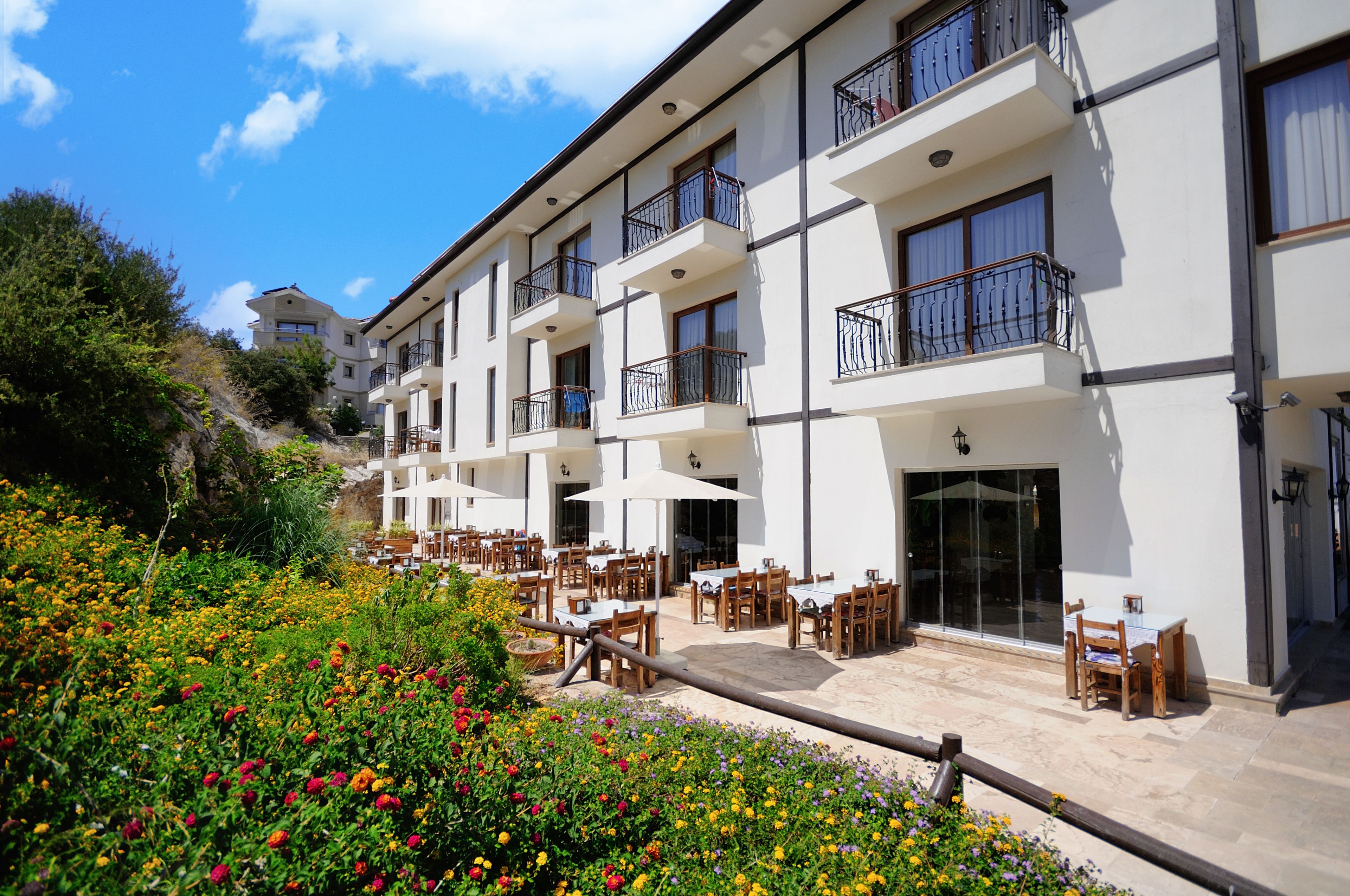 Un hotel con terraza al aire libre, balcones y un jardín.