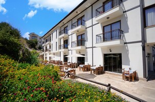 Un hotel con terraza al aire libre, balcones y un jardín.