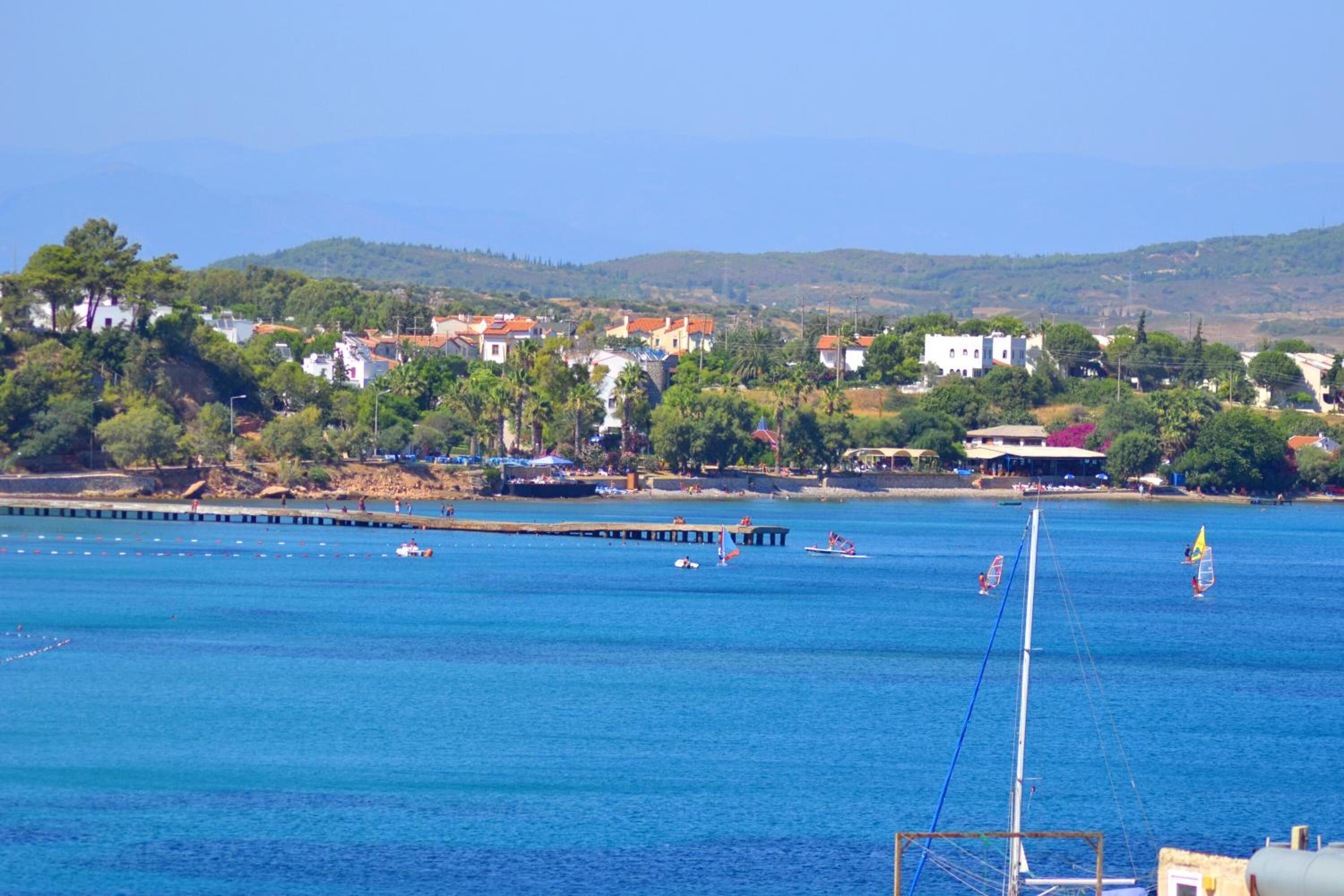 A coastal town with houses, a pier, and sailboats on the water.
