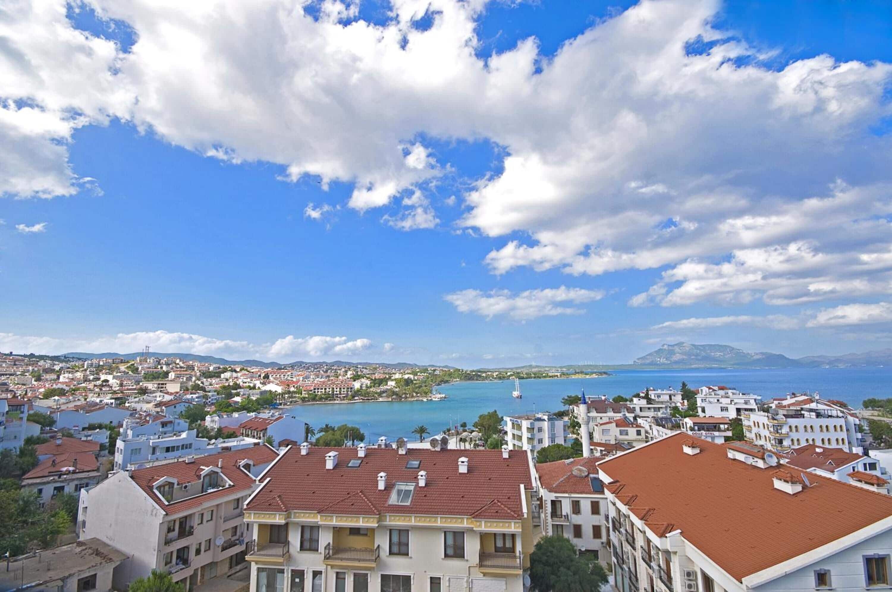 A coastal cityscape with buildings, a clear blue sky, and a view of the sea.