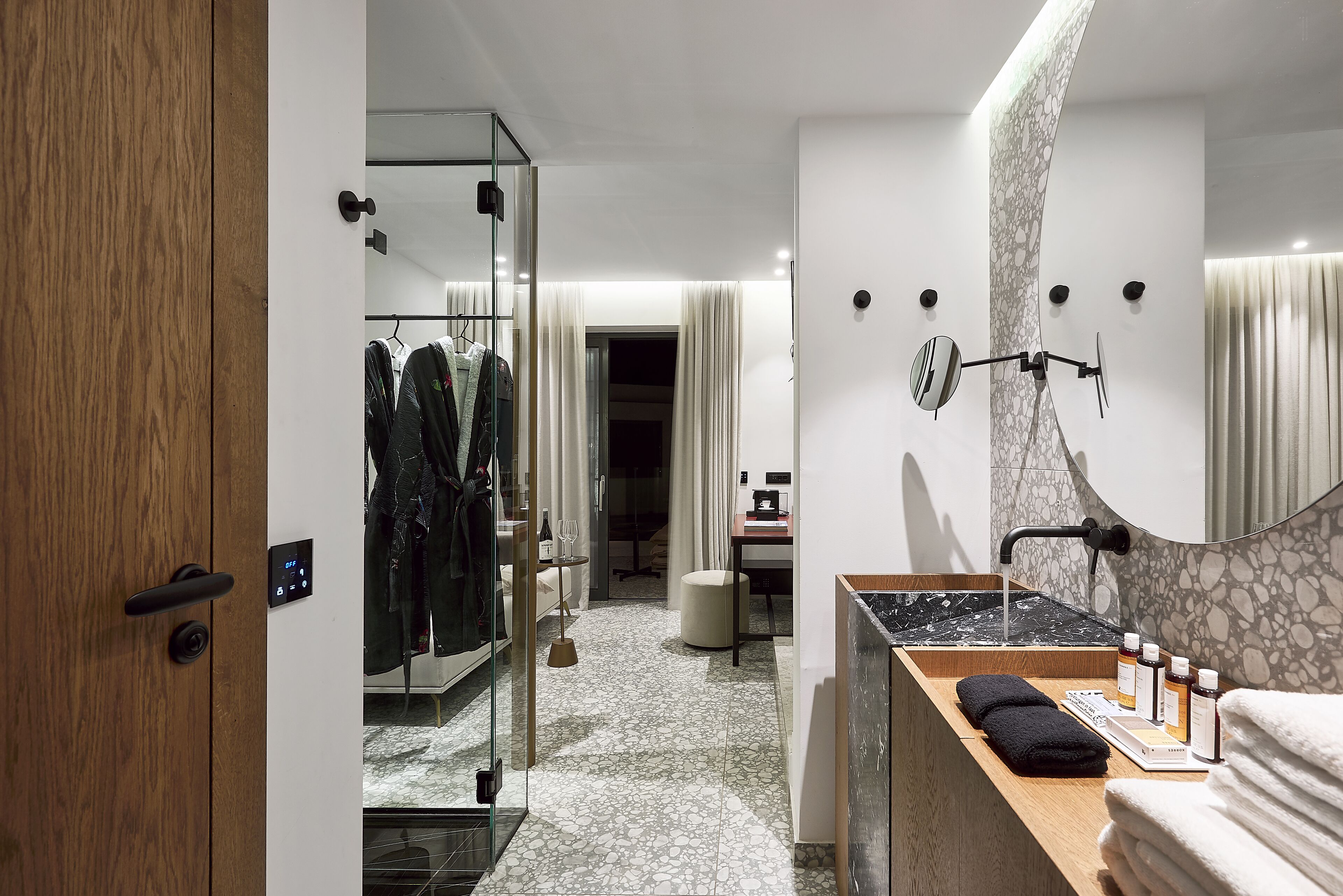 A modern bathroom with a marble sink, a glass shower enclosure, and a wooden vanity.