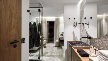 A modern bathroom with a marble sink, a glass shower enclosure, and a wooden vanity.