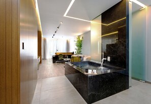 A modern bathroom with a black marble sink, a glass shower enclosure, and a wooden panel wall.