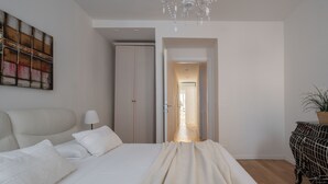 A bedroom with a bed, a bedside table, a lamp, a wardrobe, and a view of a hallway. - San Marco Prestige with Terrace by Wonderful Italy (Venice)