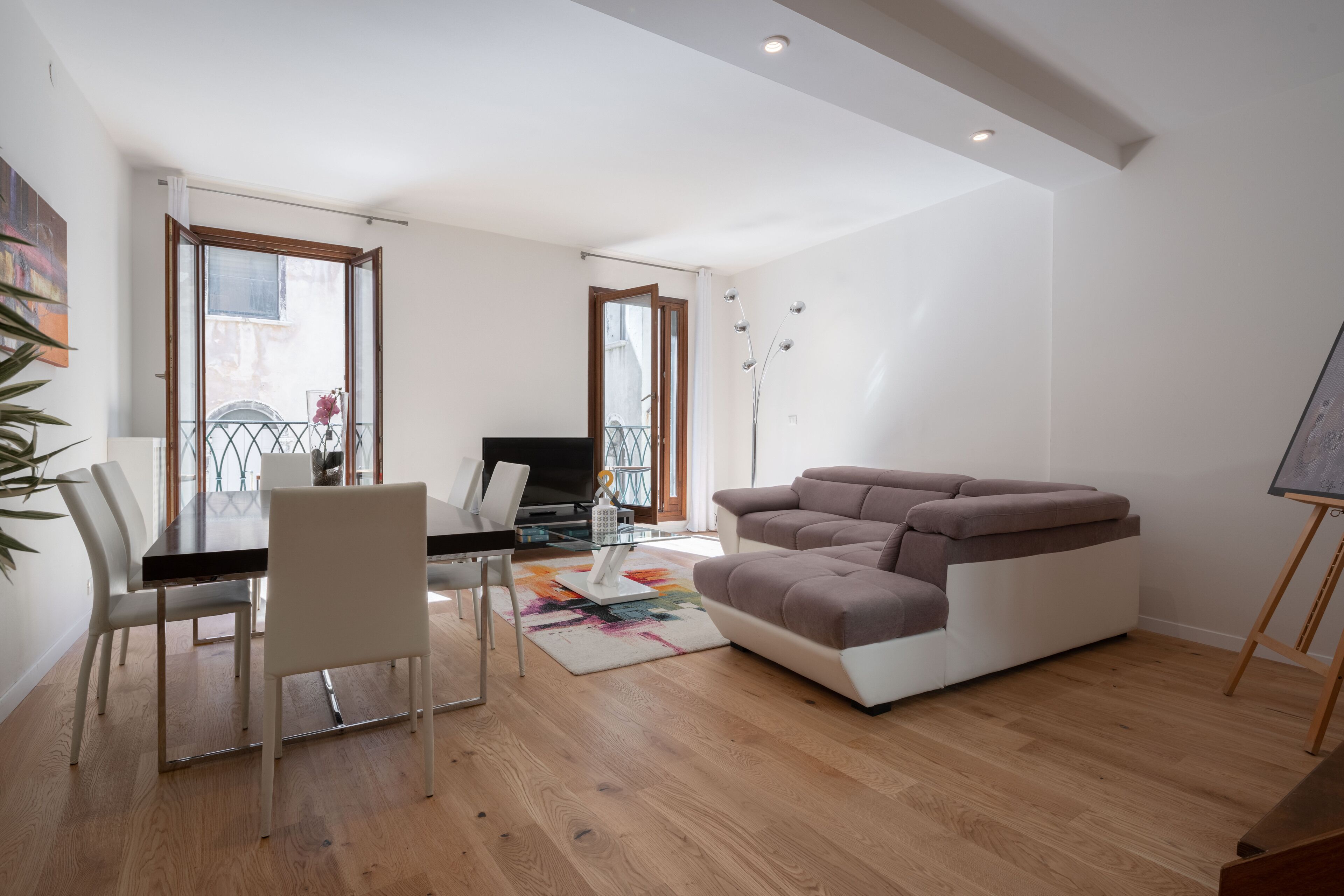 Un salon moderne avec un canapé, une table à manger et des chaises, ainsi qu’un téléviseur.
