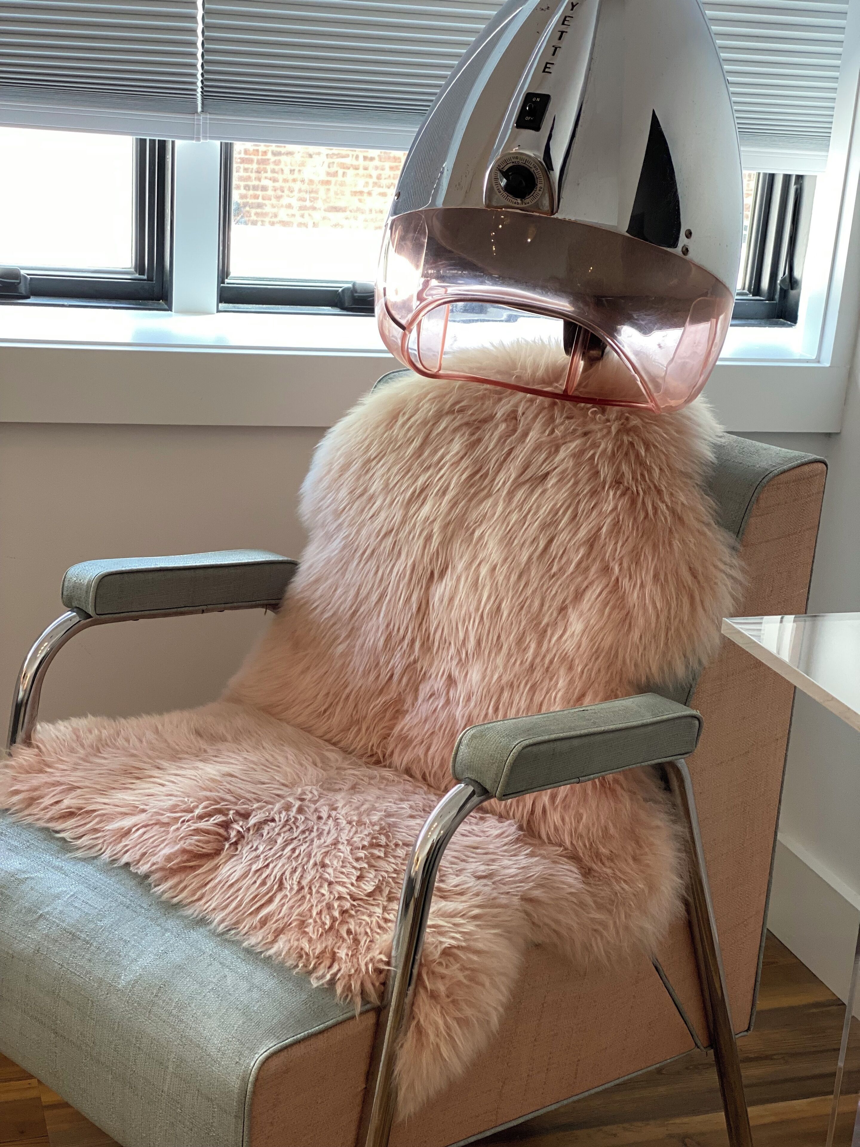 Une chaise dotée d’un coussin rose et moelleux, d’une structure en métal et d’un objet blanc posé sur le dessus.