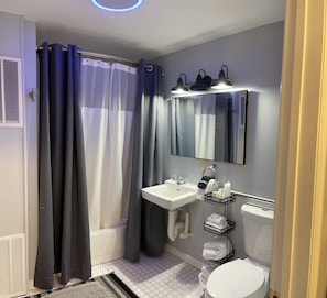 Un baño moderno con ducha, inodoro, lavamanos y toallero.