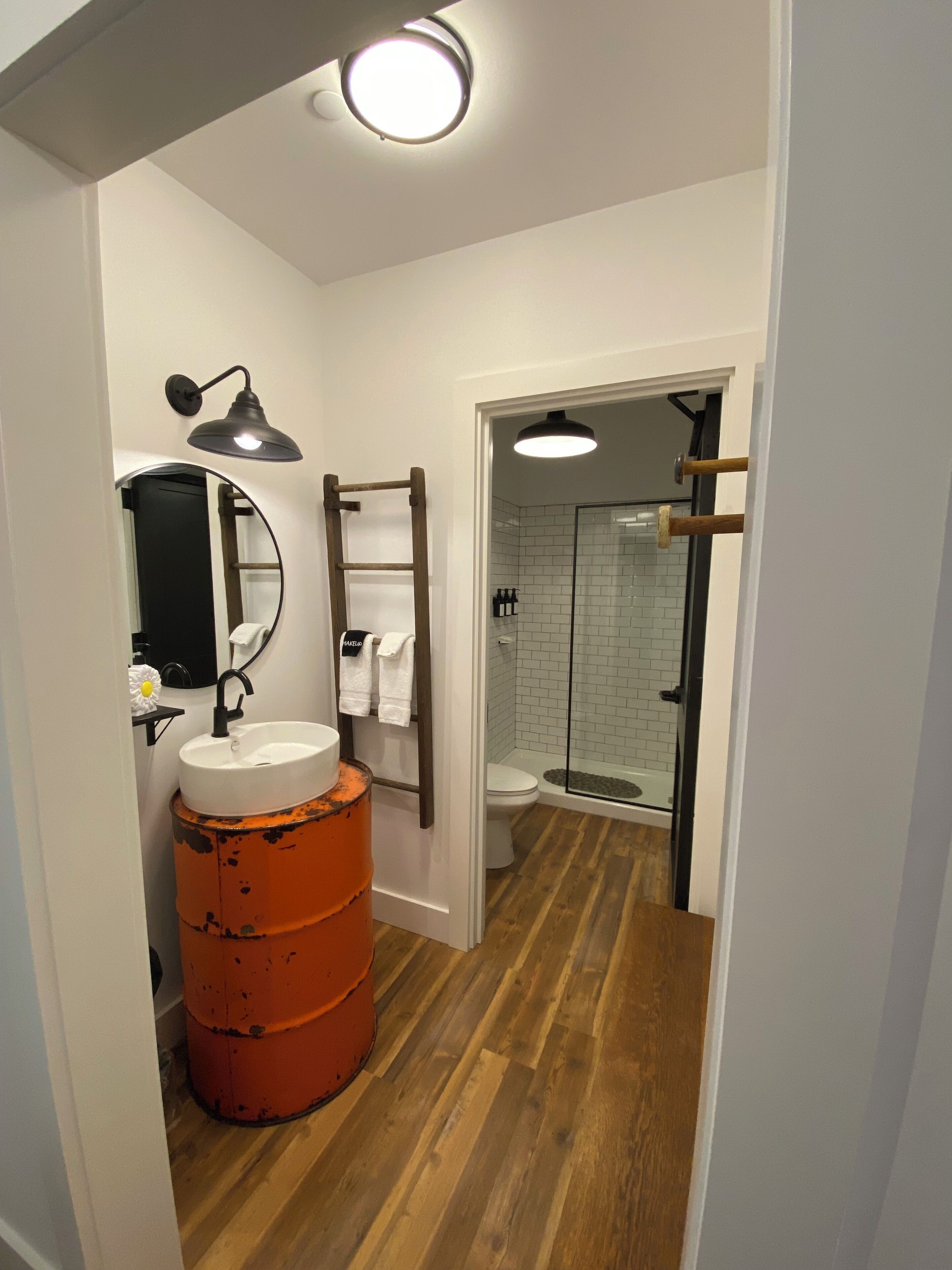 Un baño con lavamanos, espejo, toallero y zona de ducha.
