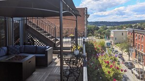 A balcony with outdoor seating, a staircase, and a view of the cityscape.