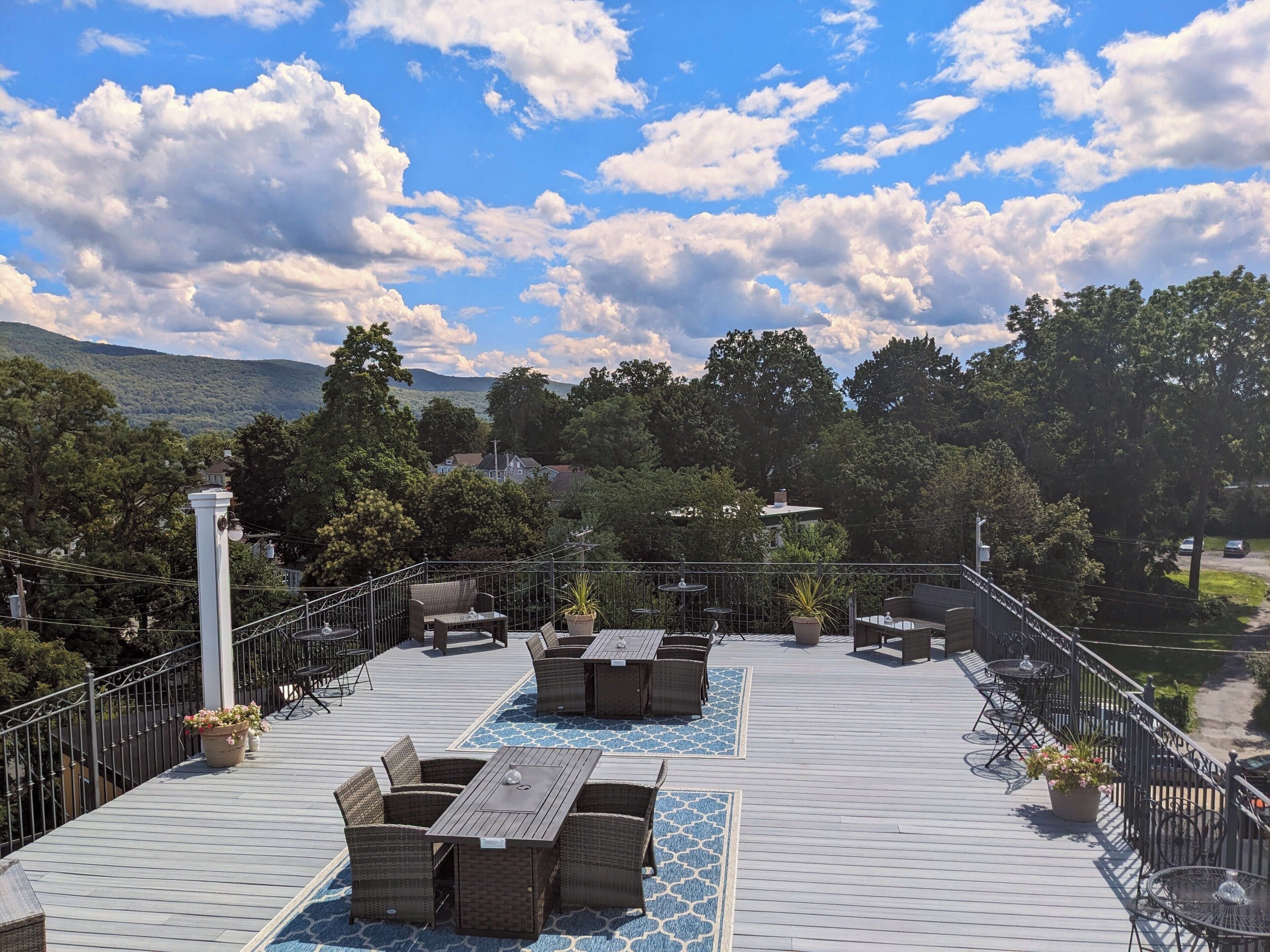 A deck with outdoor seating, surrounded by trees and a view of a hilly landscape.