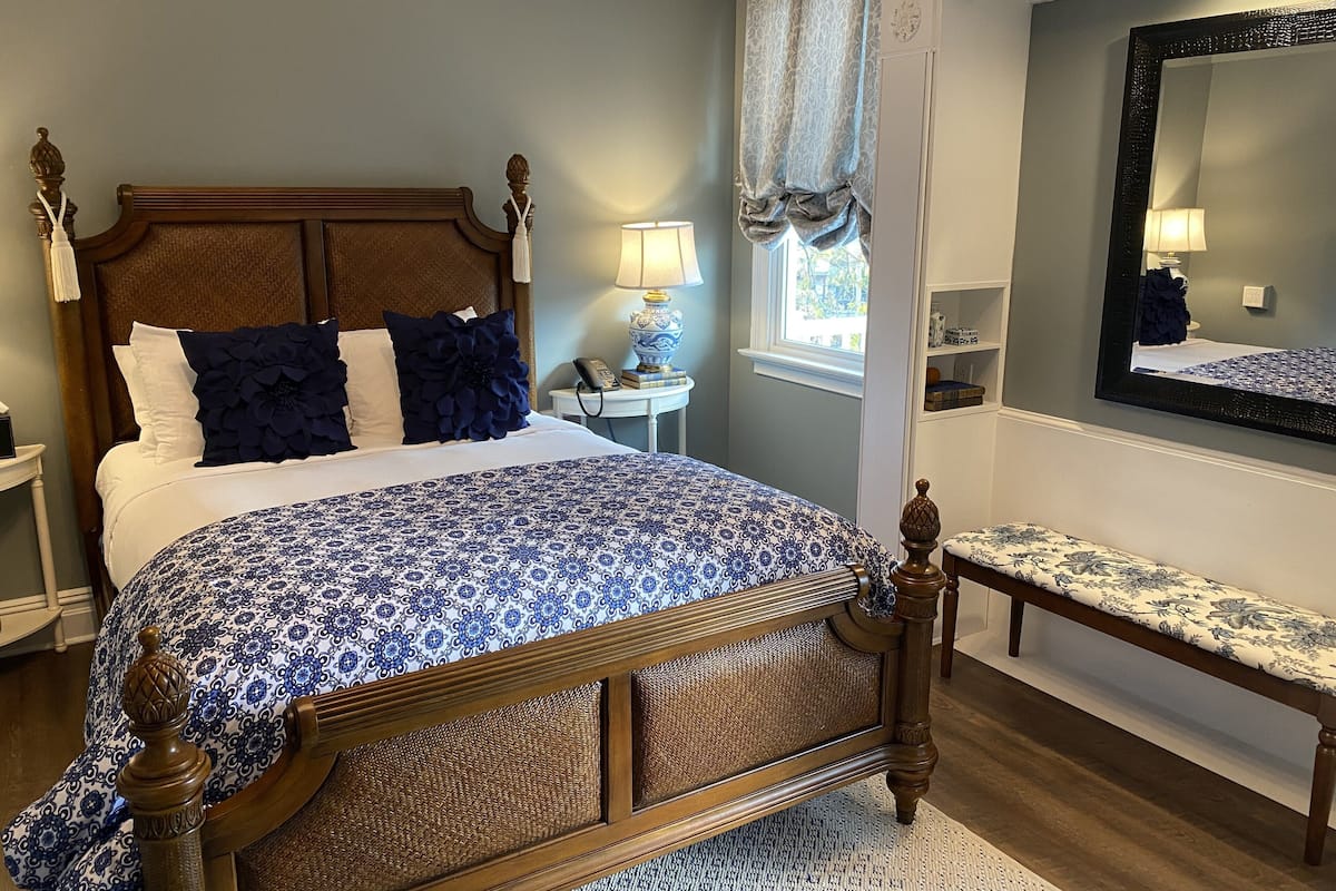 A neatly made bed with a patterned bedspread, a wooden headboard, and decorative pillows.