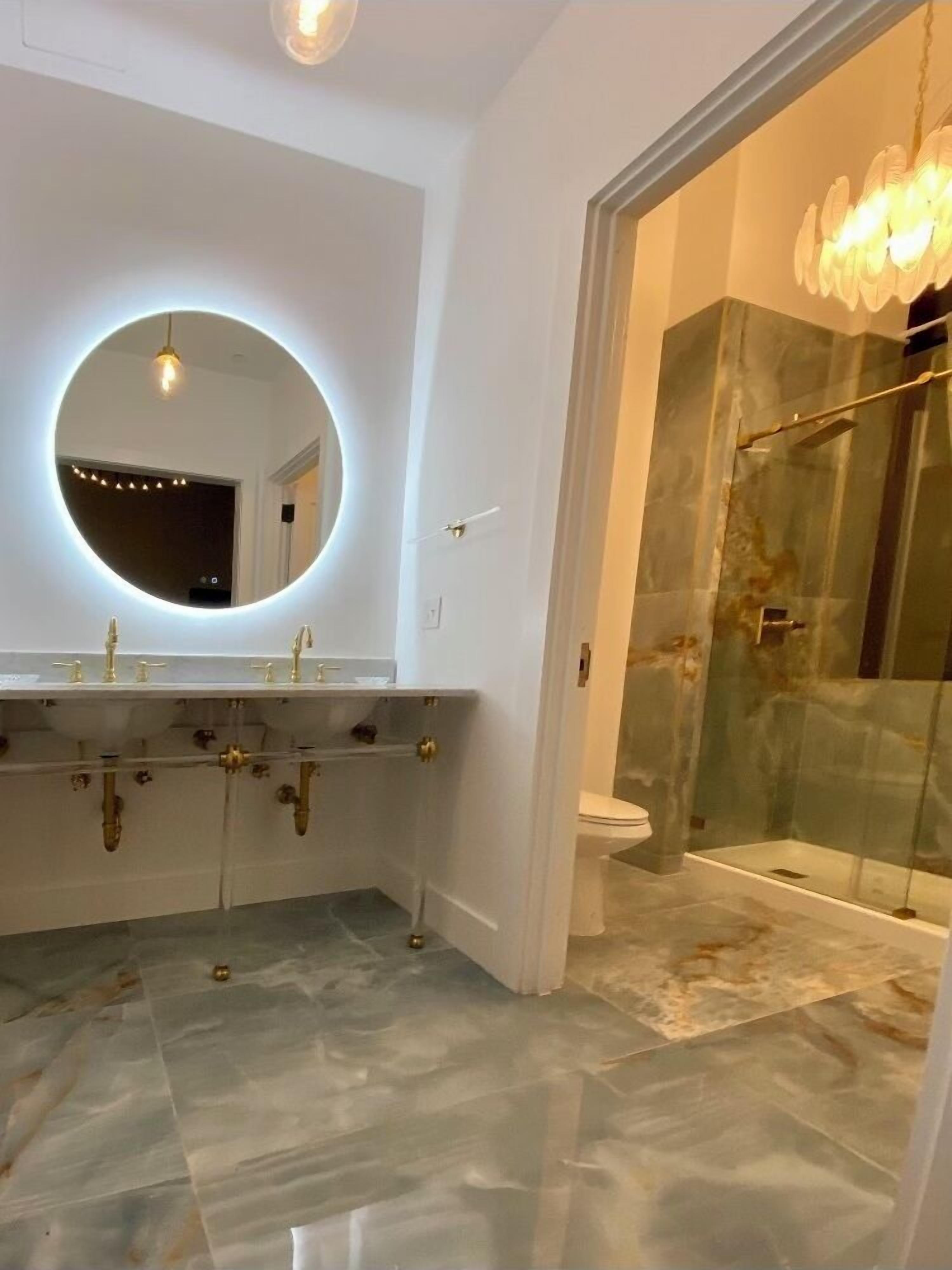 Uma casa de banho moderna com espelho redondo, duas pias e cabine de duche em vidro.