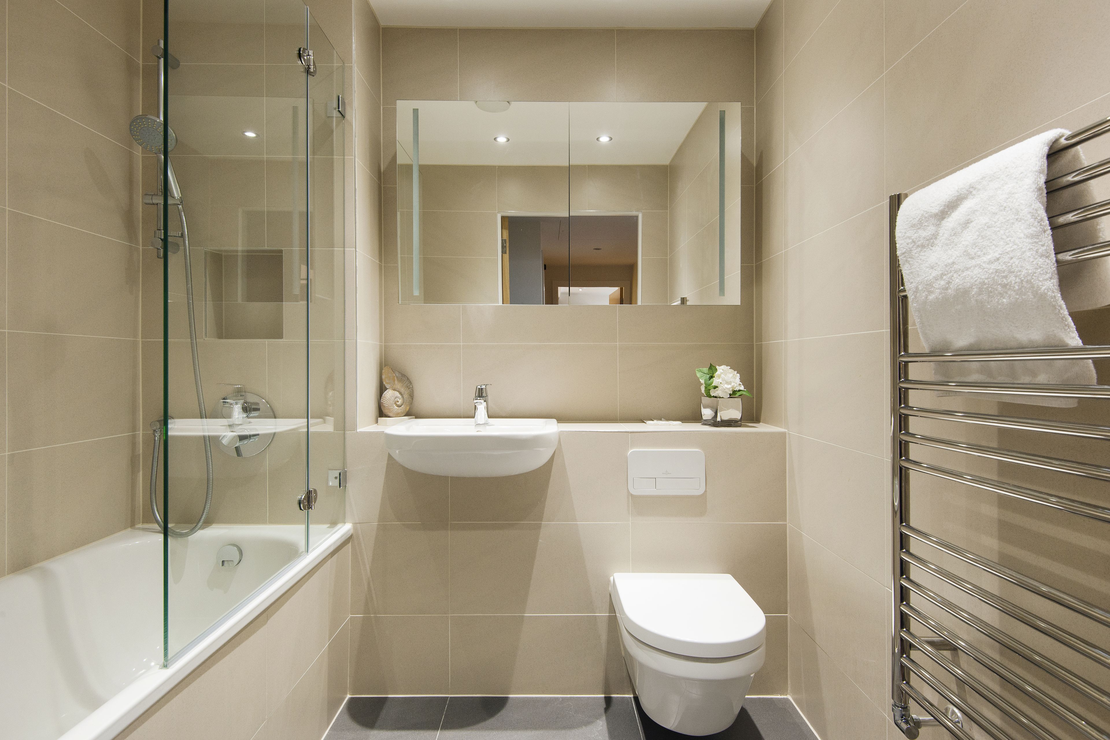 Un baño moderno con ducha de vidrio, un lavabo blanco y un inodoro.
