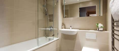 A modern bathroom with a glass-enclosed shower, a white bathtub, a sink, and a toilet.