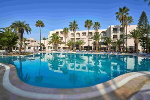Una piscina techada, una piscina al aire libre, sombrillas