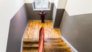 Een houten trap met een rode leuning die naar een raam leidt.