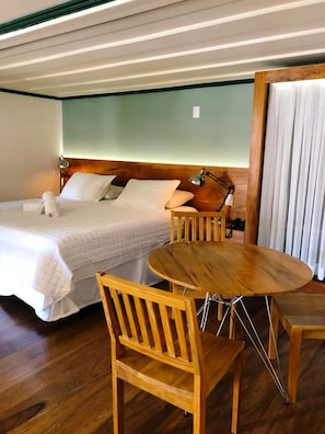 A hotel room with a bed, bedside lamps, a round wooden table, and a chair. - Pousada Vovô Chiquinho (Tiradentes)