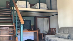 Ein Schlafzimmer im Loft-Stil mit einem Etagenbett, einem Fernseher, einer Couch und einer Treppe.
