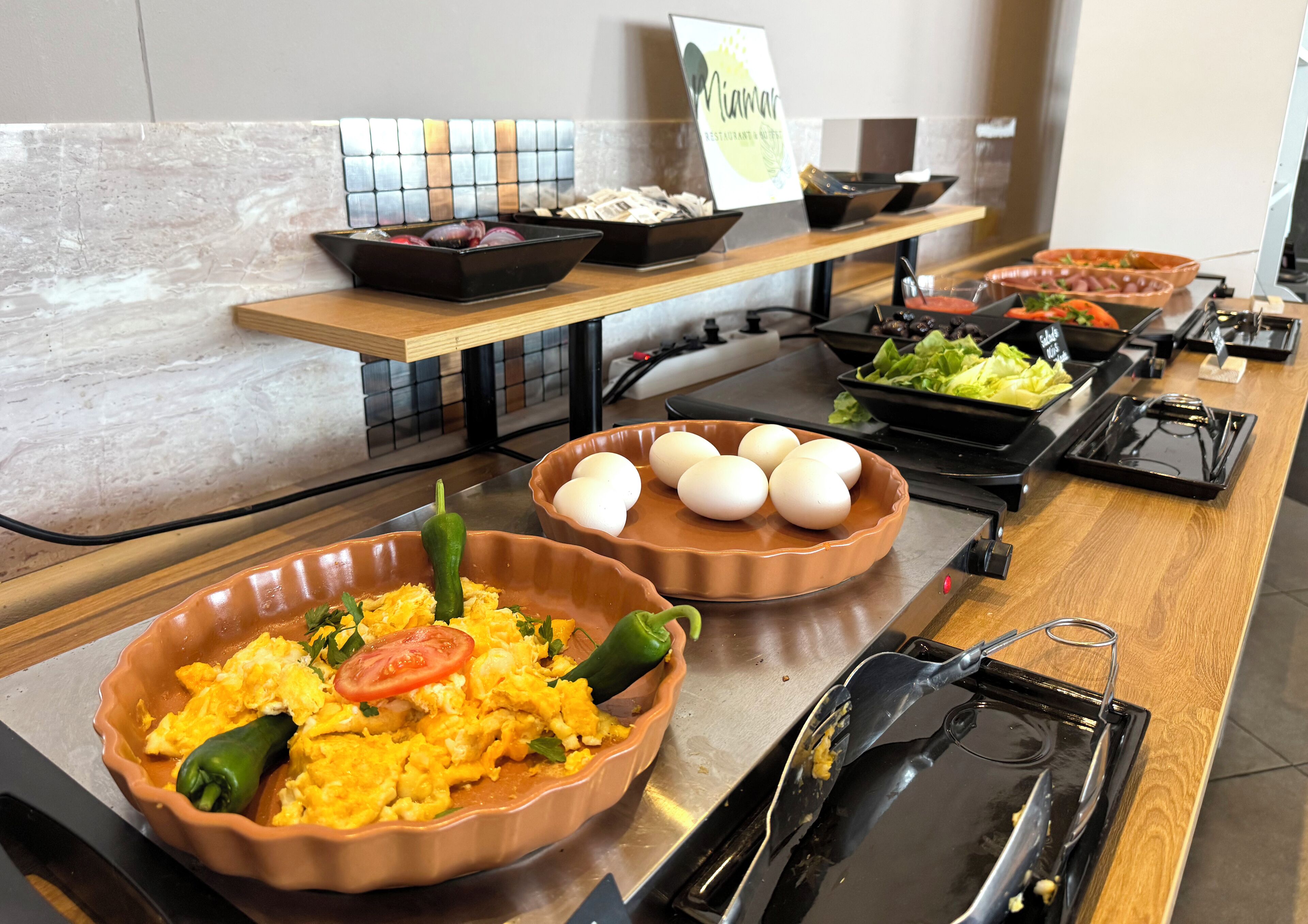 Un buffet proposant divers plats, notamment des œufs brouillés, des œufs et des légumes.