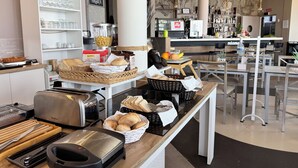 Een ontbijtbuffet met diverse gerechten, een koffieapparaat en zitplaatsen.