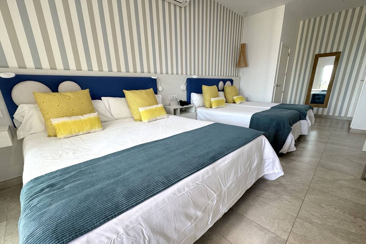 Een hotelkamer met twee bedden, gestreepte behang en een grote spiegel.