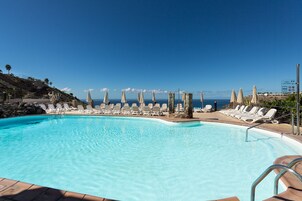 Una piscina al aire libre, sillones reclinables de piscina