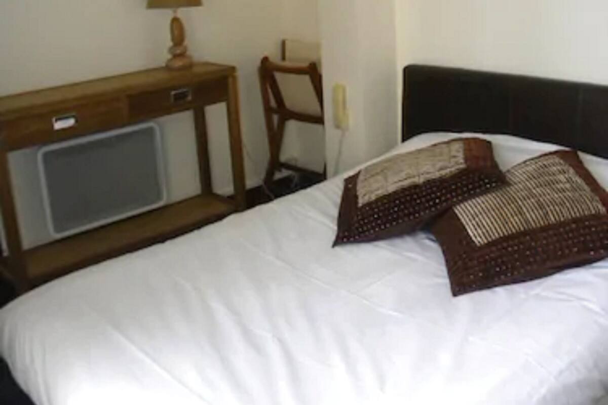 Ein Hotelzimmer mit einem Bett, einem Schreibtisch, einem Sessel und einer Wandlampe.