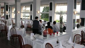 A restaurant with white tables and chairs, large windows, and a view of the outdoors. - Normotel - La Marine (Rives-en-Seine)