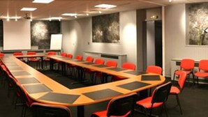 A conference room with a long table, red chairs, and a projector screen. - Normotel - La Marine (Rives-en-Seine)