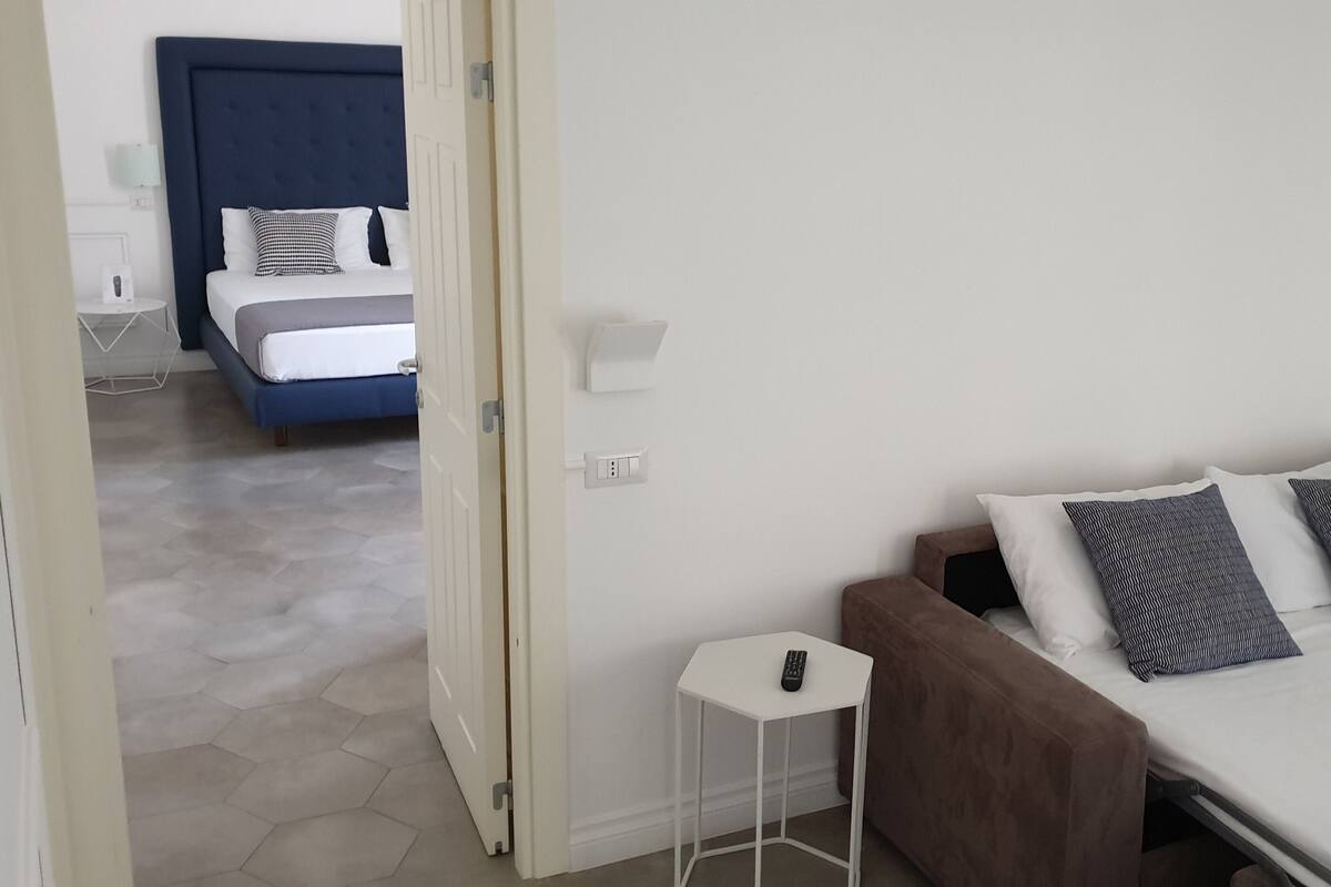 Une chambre d’hôtel avec un lit, une petite table de chevet et une commode.