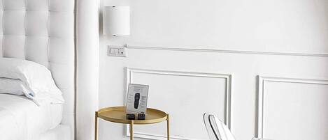 A modern bedroom with a tufted headboard, a bedside table with a remote control, and a wall-mounted light fixture.