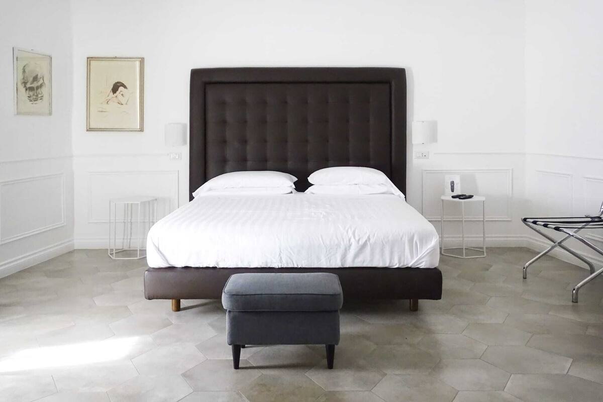 Une chambre moderne avec un grand lit, une table de chevet, une chaise et une lampe sur pied.