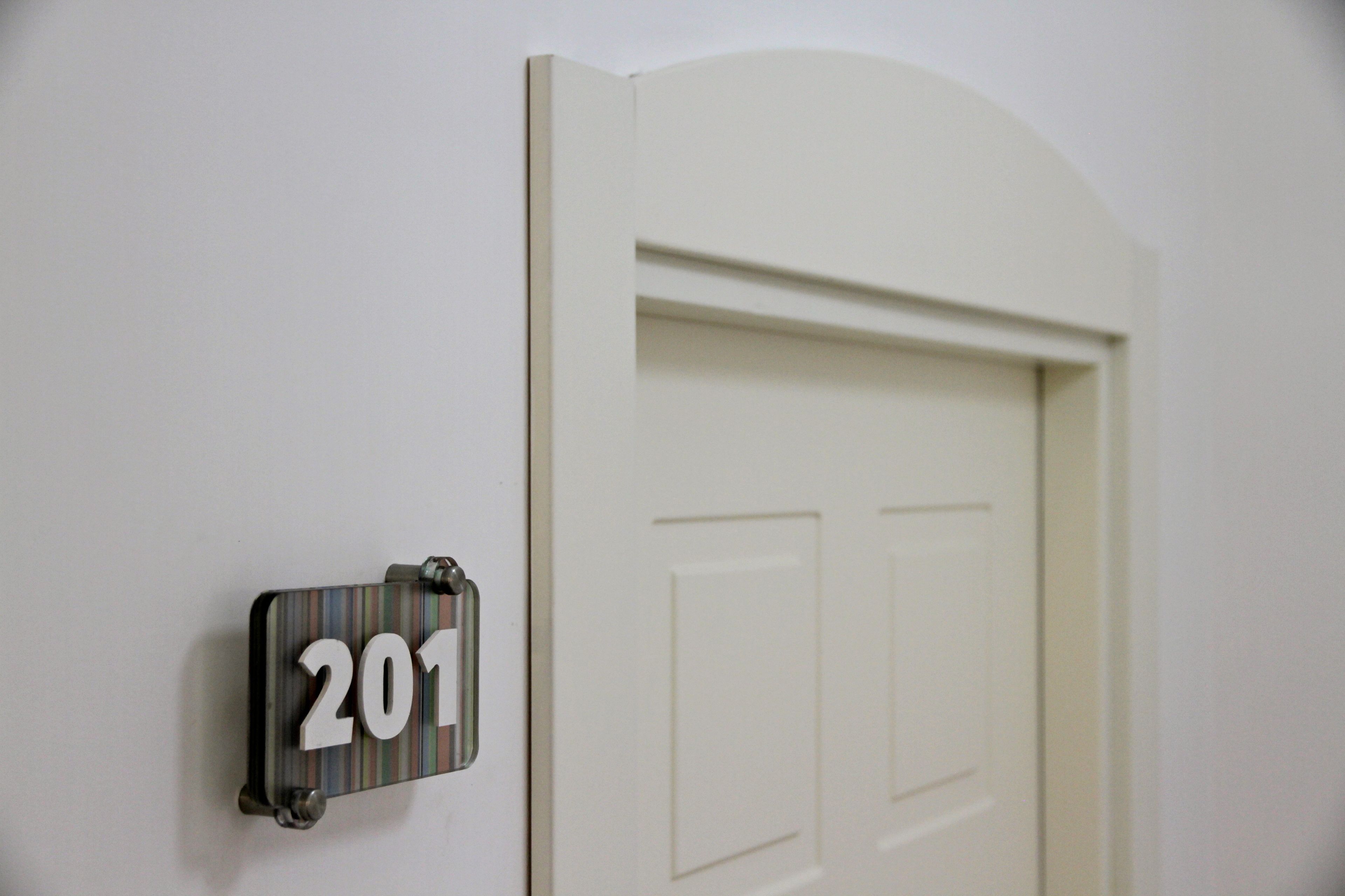 Une porte avec une plaque portant le numéro « 201 » est fixée au mur.