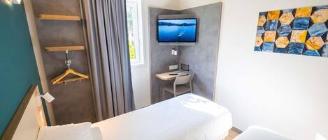 Una habitació d'hotel amb llit, escriptori, televisió i bany.