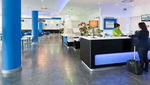 A modern hotel reception area with a reception desk, seating area, and a reception sign.