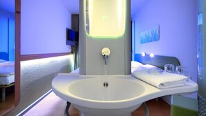 A modern bathroom with a white sink, a mirror, and a towel rack.