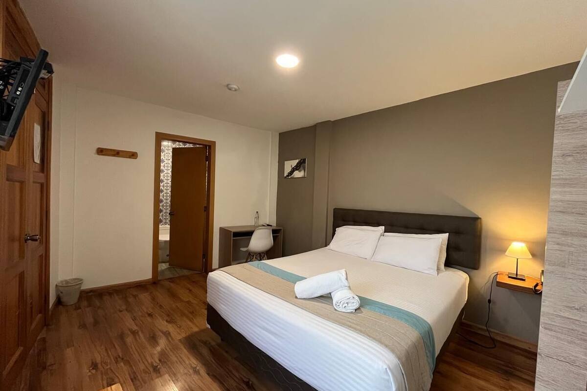 Una habitación de hotel ordenada con cama, escritorio y una silla.