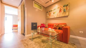 Un salon moderne avec une table basse en verre, un canapé rouge et un tableau accroché au mur.