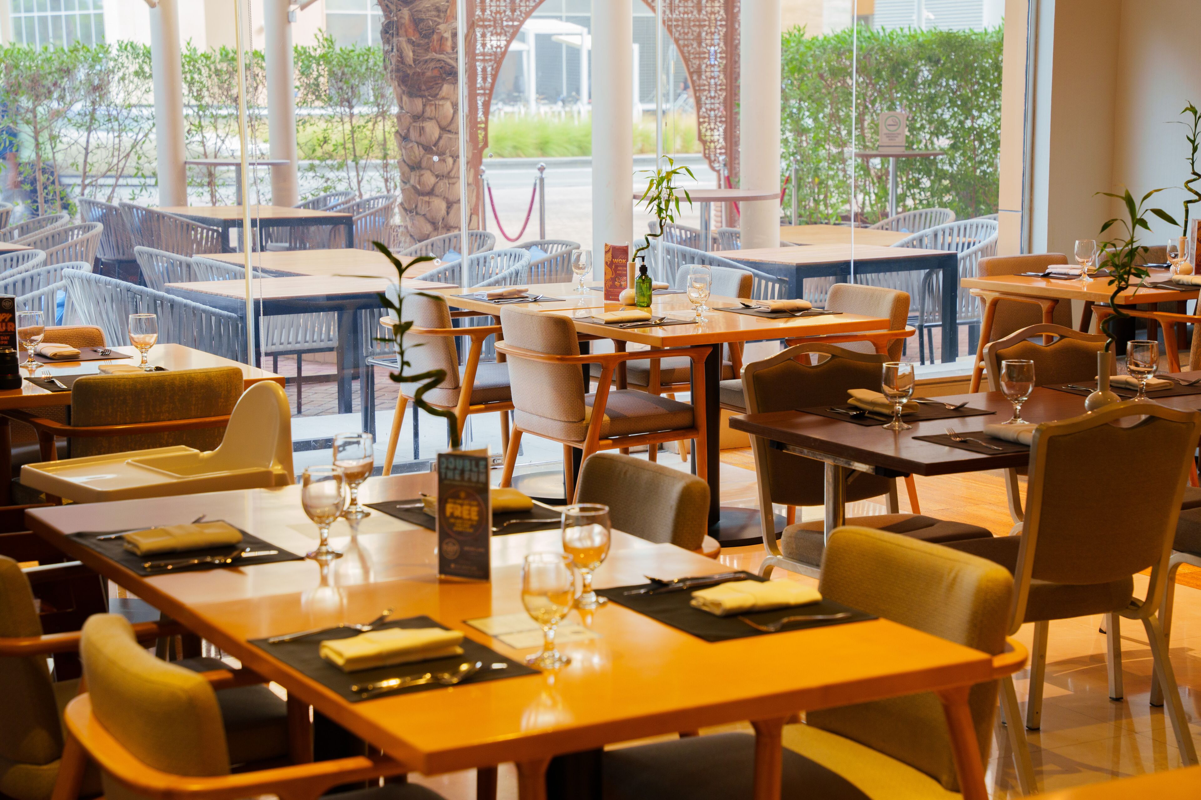 A restaurant with multiple tables and chairs, some with menus and glasses of water.