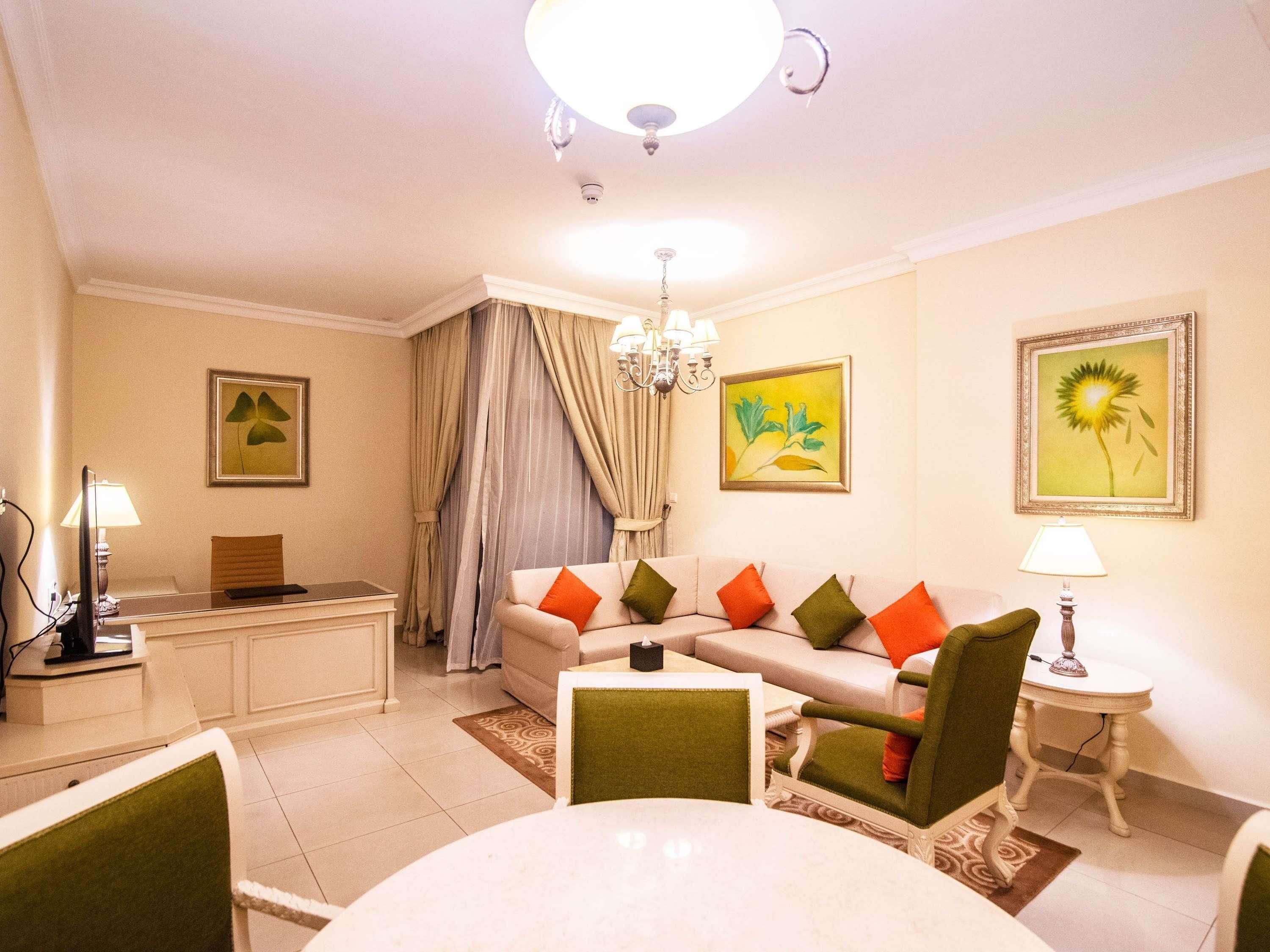 A living room with a sofa, chairs, a dining table, a chandelier, and artwork on the walls.