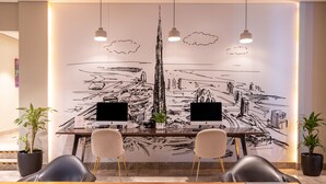 Une salle de conférence moderne dotée d’une grande fresque murale, de deux écrans et de sièges confortables.