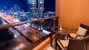 A balcony with a view of a cityscape at night, featuring illuminated skyscrapers and a busy road below.