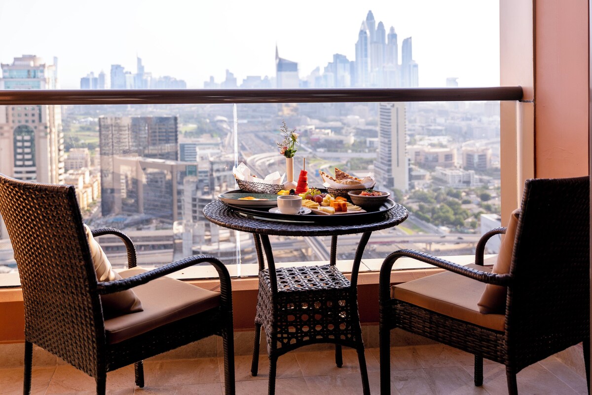 Un balcon avec des fauteuils en osier et une table ronde sur laquelle est disposée une variété de plats.
