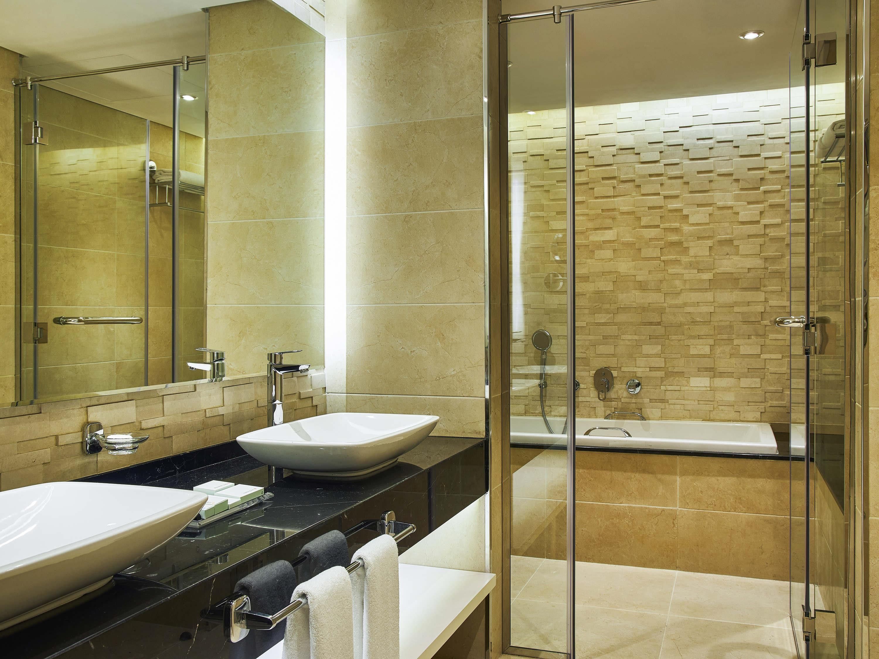 A modern bathroom with two sinks, a glass-enclosed shower, and a large mirror.