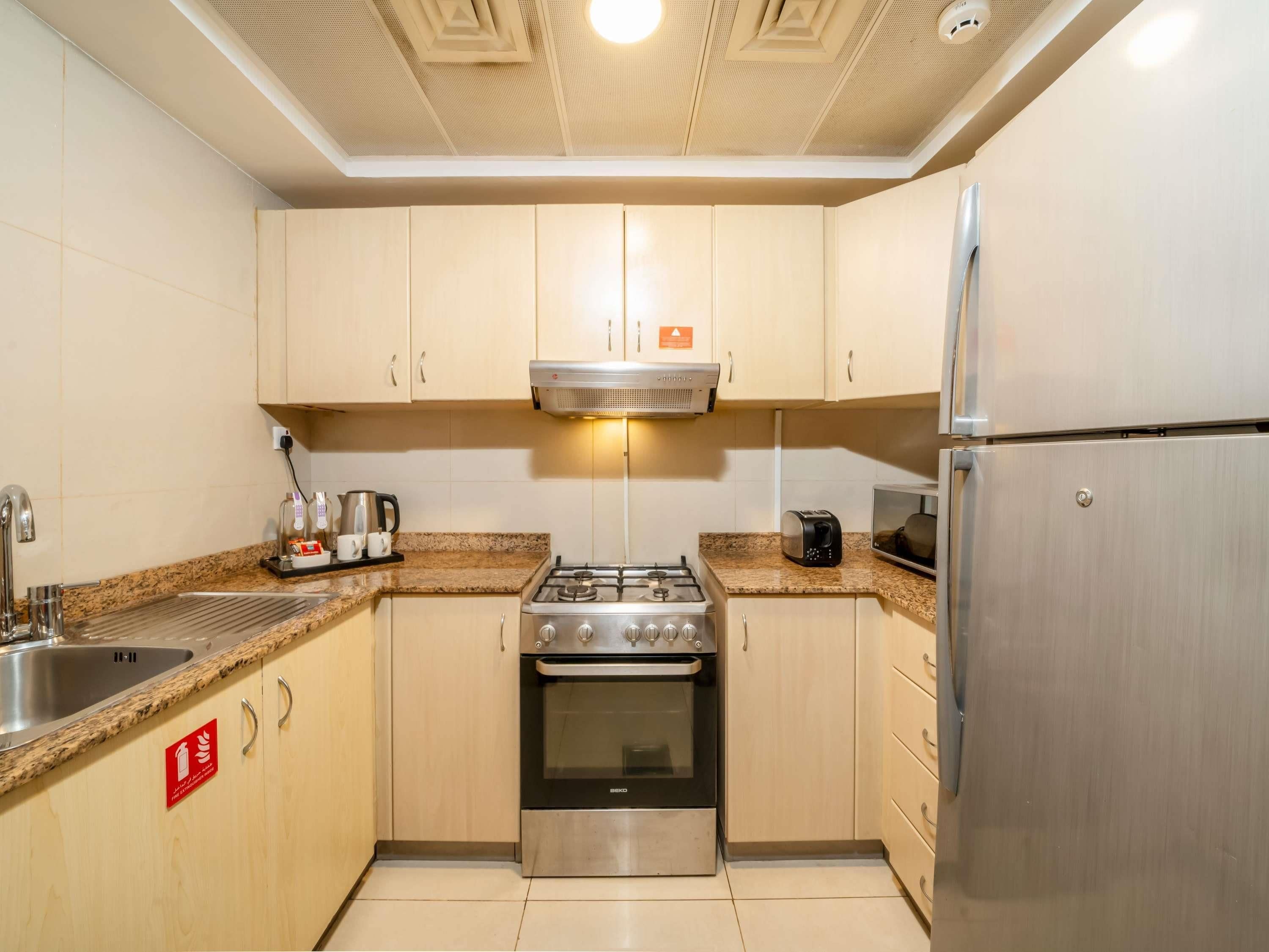 A modern kitchen with a gas stove, oven, microwave, and stainless steel refrigerator.