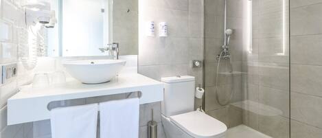 Un baño moderno con lavamanos, inodoro y ducha blancos.