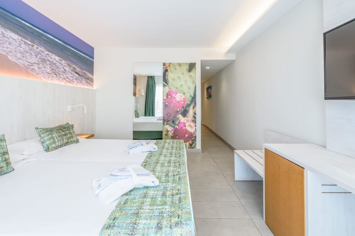 A hotel room with a large bed, a desk, and a TV mounted on the wall.
