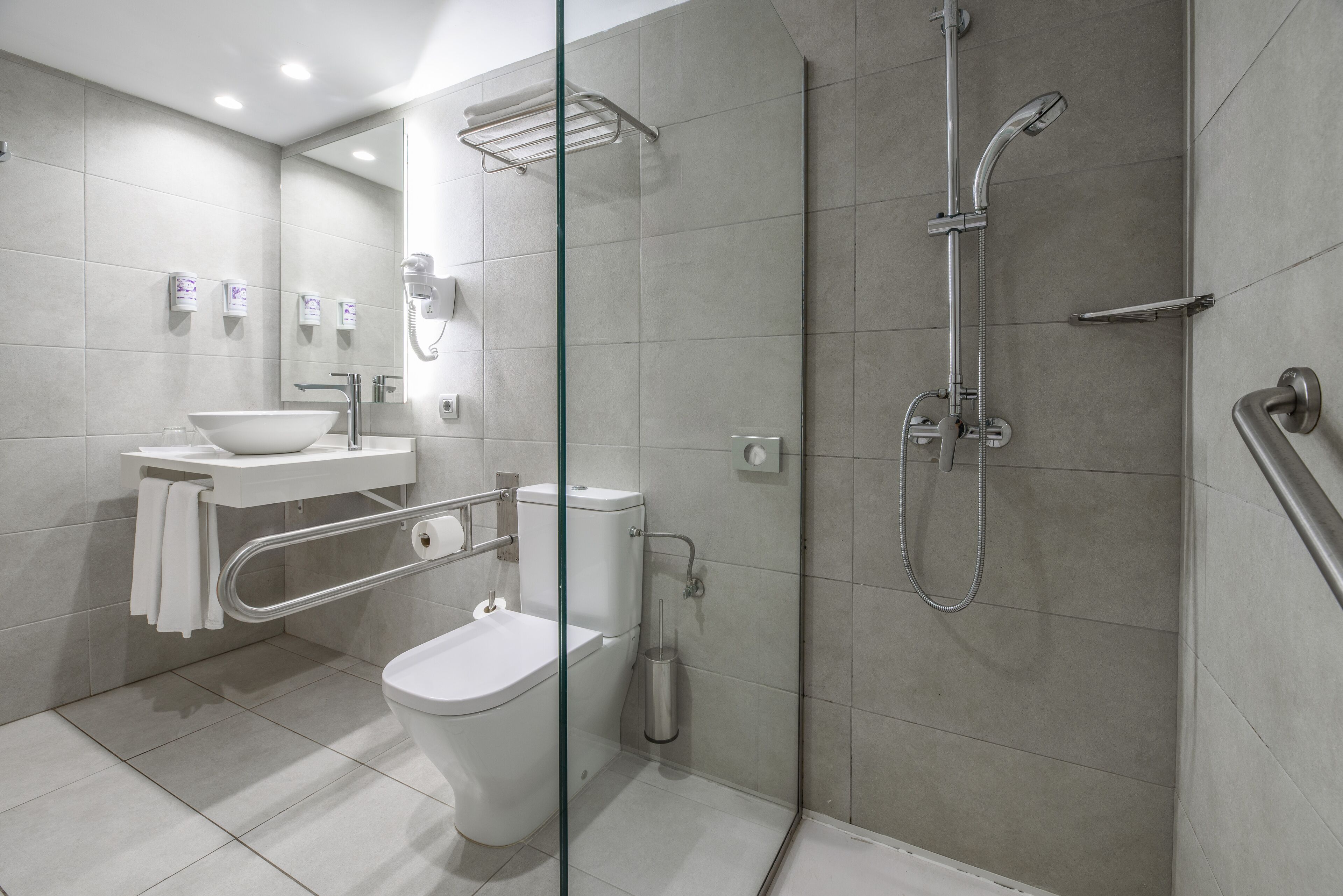 A modern bathroom with a glass partition, a toilet, a sink, and a shower area.