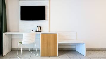 Une chambre moderne avec un bureau blanc, une chaise, un banc en bois et un téléviseur à écran plat fixé au mur.